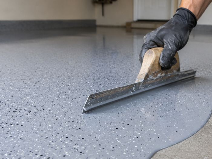 Flake coat being spread by hand on a basement slab